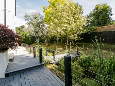 A garden pathway with wooden deck and railing surrounded by trees and plants at Iroko in Millbrook