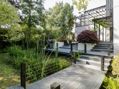 A garden deck with steps, plants, a barbecue grill, and seating at Iroko in Millbrook