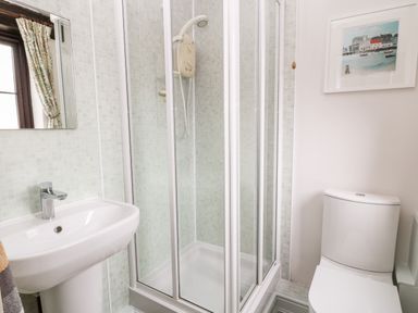 A bathroom with a shower enclosure a sink a toilet and a framed picture on the wall at Wagtail in Bradworthy near Bude