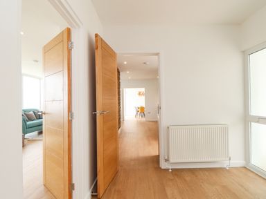 A hallway with wooden doors and a radiator along a wall at Boscregan in Porthleven