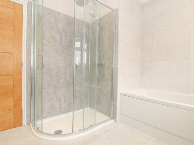 A bathroom with a glass shower enclosure and a white bathtub at Boscregan in Porthleven