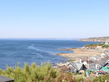 A coastal view with houses near rocky shoreline and blue sea at Boscregan in Porthleven