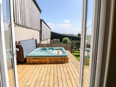 A wooden deck with a hot tub and a bottle on the edge at Lovesome Pod Lovesome Hill near Northallerton