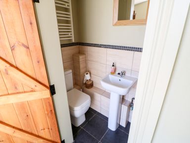 A small bathroom with a toilet sink mirror and wooden door at Lovesome Pod Lovesome Hill near Northallerton