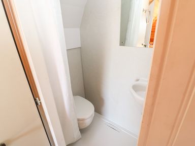 A small bathroom with a toilet a sink a mirror and a shower curtain at Lovesome Pod Lovesome Hill near Northallerton