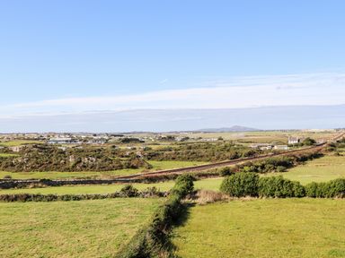 A rural landscape with green fields and a railway track stretching across at Plas Newydd in Llanfaelog near Rhosneigr