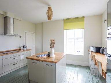A kitchen with an island table utensils and appliances at Plas Newydd Llanfaelog near Rhosneigr