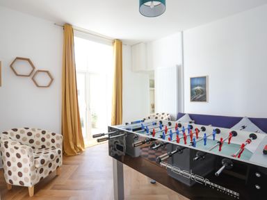 A room with a foosball table polka dot armchairs yellow curtains and framed picture at Plas Newydd in Llanfaelog near Rhosneigr