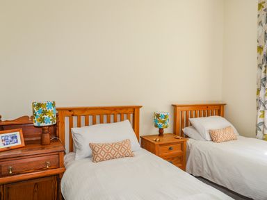 A bedroom with two single beds wooden headboards bedside tables and patterned lamps at Plas Newydd in Llanfaelog near Rhosneigr