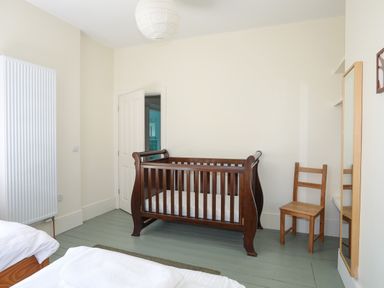 A bedroom with a wooden baby crib chair and mirror at Plas Newydd in Llanfaelog near Rhosneigr