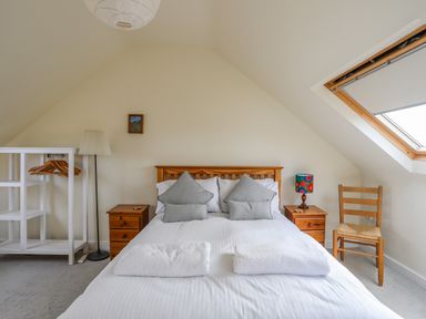 A bedroom with a double bed two nightstands a chair a lamp and a skylight window at Plas Newydd Llanfaelog near Rhosneigr