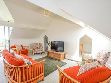 A living room with orange sofas and patterned armchairs at Plas Newydd in Llanfaelog near Rhosneigr