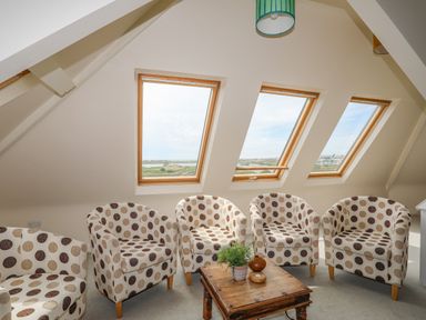 A seating area with five polka dot armchairs and a wooden coffee table under three skylight windows at Plas Newydd in Llanfaelog near Rhosneigr
