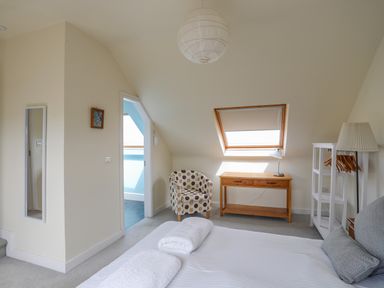 A bedroom with a bed towels on a bed polka dot armchair desk and window at Plas Newydd in Llanfaelog near Rhosneigr