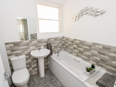 A bathroom with a toilet sink bathtub gray towel and decorative fish on the wall at Garth in Pen-y-bryn near Cardigan
