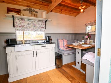 A small kitchen with a sink toaster and kettle next to a dining nook with a table set for four at The Lazy Mare by The Water Admaston near Abbots Bromley