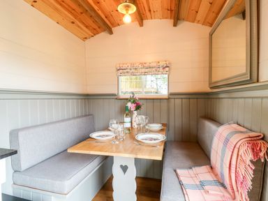 A dining nook with a wooden table set for four and cushioned bench seating at The Lazy Mare by The Water in Admaston near Abbots Bromley