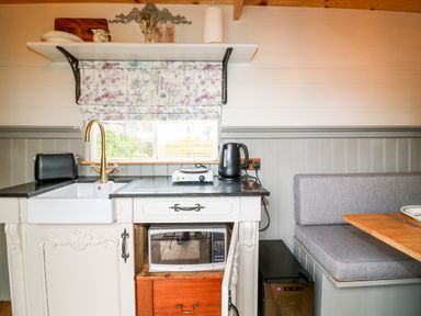 A kitchen area with a sink a toaster a kettle a microwave and a built in bench seat at The Lazy Mare by The Water Admaston near Abbots Bromley
