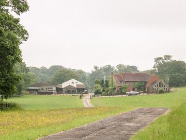 A country house and farm buildings surrounded by green fields and trees at The Lazy Mare by The Water Admaston near Abbots Bromley