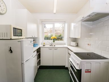 A kitchen with a refrigerator microwave stove toaster and a window with flowers on the sill at Ty Twmp Tump Cottage Tal-Y-Bont-On-Usk