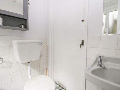 A bathroom with a toilet sink mirror and closed door at Ty Twmp Tump Cottage in Tal-Y-Bont-On-Usk
