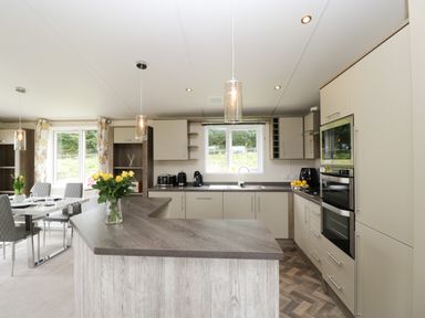 A kitchen with beige cabinets a wooden countertop and a vase of yellow flowers at Hill View Lilac Lodge in Wareham