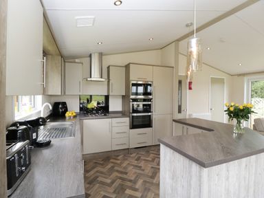A kitchen with grey countertops and cabinets a stove oven and toaster with yellow flowers on a counter at Hill View Lilac Lodge in Wareham