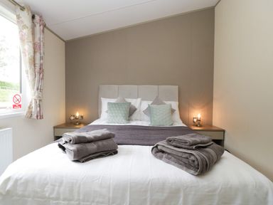 A bedroom with a bed and pillows and towels on the bed at Hill View Lilac Lodge in Wareham