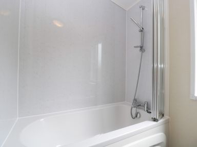 A bathroom with a white bathtub and a showerhead at Hill View Lilac Lodge in Wareham