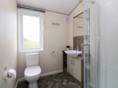 A bathroom with a toilet sink with cabinet mirror shower and window at Hill View Lilac Lodge in Wareham