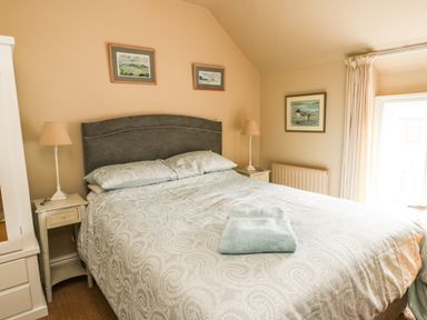 A bedroom with a double bed two bedside tables with lamps and framed pictures above the bed at Silva in Penmon