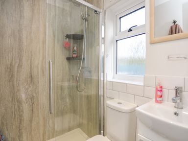 A bathroom with a glass shower enclosure a toilet a sink a window and a mirror at Silva in Penmon