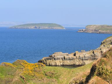 A coastal landscape with cliffs and an island in the sea at Silva in Penmon