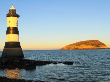 A lighthouse by the sea with an island in the background at Silva in Penmon