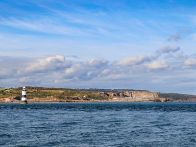 A coastal landscape with a lighthouse and cliffs by the sea at Silva in Penmon