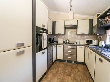 A kitchen with cabinets appliances a microwave and a sink at RoseGrace Lodge in Auchterarder