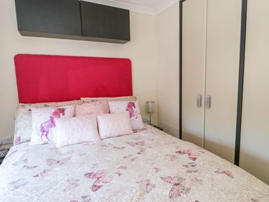 A bedroom with a bed with butterfly and horse patterned bedding and pink headboard at RoseGrace Lodge in Auchterarder