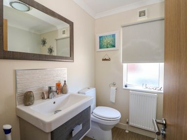 A bathroom with a sink and mirror toilet window with blind and radiator at RoseGrace Lodge in Auchterarder