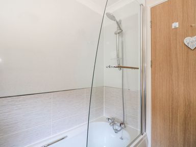 A bathroom with a bathtub shower combination and a wooden door at RoseGrace Lodge in Auchterarder