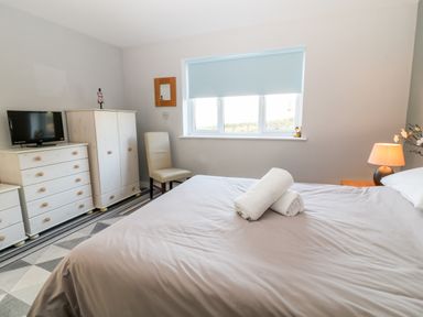 A bedroom with a bed towels on top and furniture including a wardrobe chest of drawers and a chair at Seagull Cottage in Bude