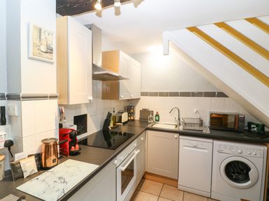 A kitchen with appliances including an oven stovetop dishwasher washing machine and microwave at Coln Cottage in Stow On The Wold