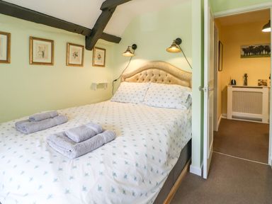 A bedroom with a double bed and folded towels on it next to a hallway at Coln Cottage in Stow-On-The-Wold