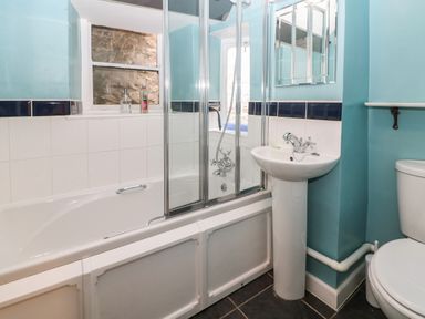 A bathroom with a bathtub shower combination sink toilet and a small window at Coln Cottage in Stow-On-The-Wold