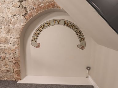 A stone archway with Welsh text painted on the wall at The Poppy Fields Abode in Dyserth