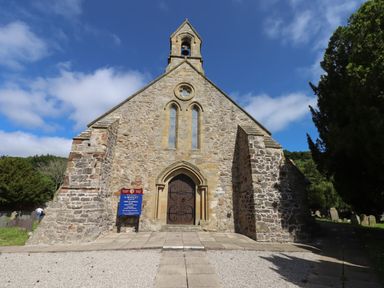 Front view of a stone church building with a wooden door and bell tower at The Poppy Fields Abode in Dyserth