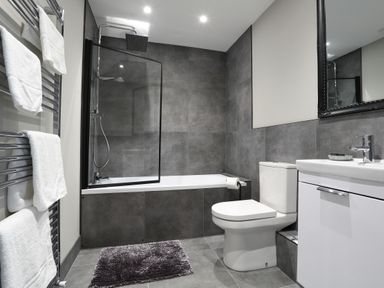 A bathroom with a bathtub shower combination toilet sink and towel rack at The Poppy Fields Abode in Dyserth
