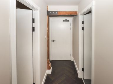 A hallway with doors on both sides and a wooden beam above a white door at The Sigma Penthouse in Dyserth
