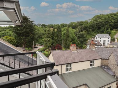 A balcony overlooking rooftops trees and a few houses at The Sigma Penthouse in Dyserth