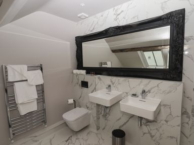A bathroom with two wall-mounted sinks a toilet a large framed mirror and a towel rack at The Sigma Penthouse in Dyserth