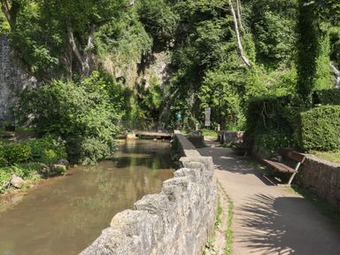A pathway beside a water canal with benches and greenery at The Sigma Penthouse in Dyserth